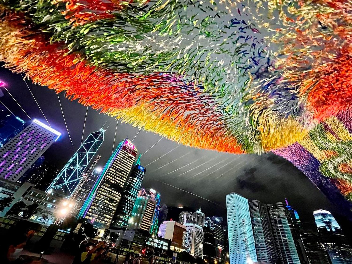 River of Light, part of the infamous Skynet Art Series, by Patrick Shearn of Poetic Kinetics at night with the city of Hong Kong behind it.